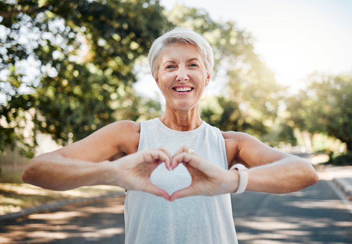 Smiling women shaping a heart with her hands.