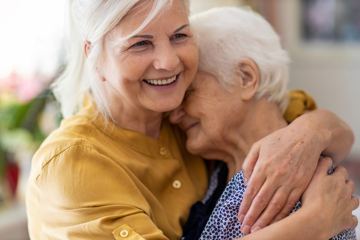 A companion volunteer embracing an older woman.