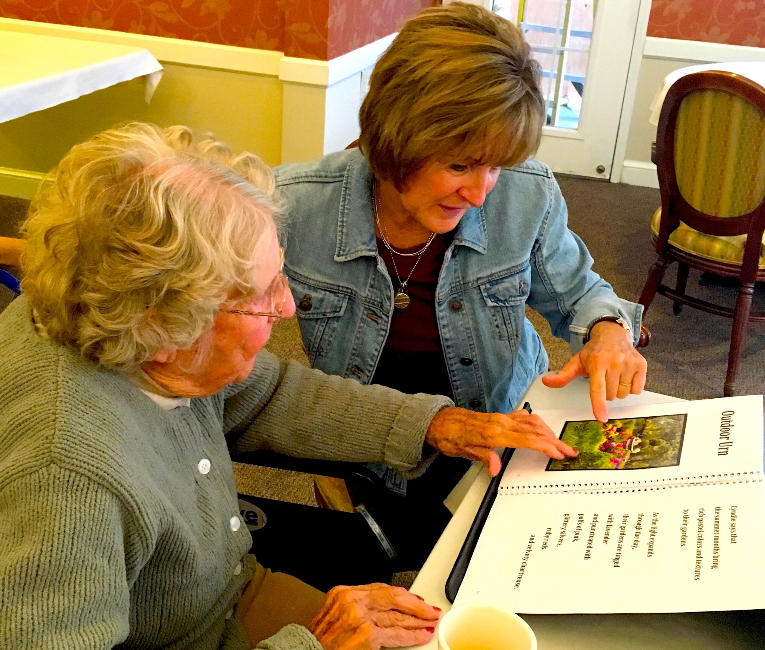 Volunteer and older woman reading a book together